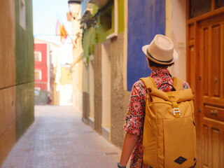 Fototapeta premium Woman strolls through colorful streets of Spanish coastal town
