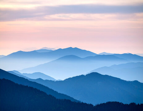 A serene and atmospheric background featuring layered silhouettes of mountain