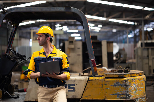 warehouse worker working on laptop computer : Hispanic latin man staff driving forklift in industrial container factory warehouse. Worker communicate by walkie talkie transmitter, radio
