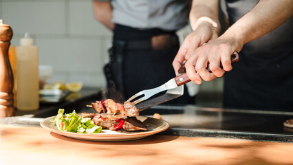 Chef plating grilled meat skewers with salad on a wooden counter