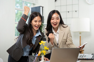 Celebrating Success in Business. Two women expressing joy over a successful project outcome.
