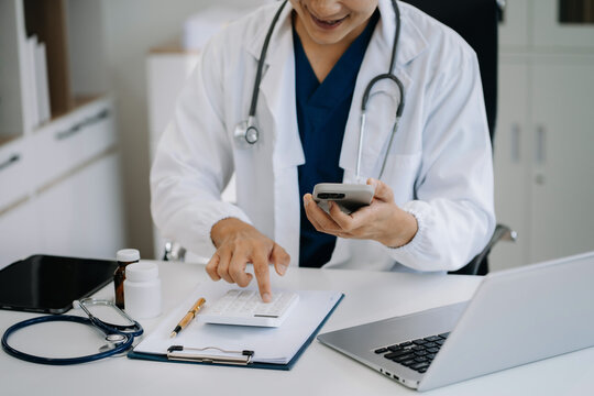 Doctor physician with stethoscope calculate medical fee costs or revenue. practitioner use calculator at Clinic.