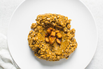 Overhead view of nigerian fried beans and fried plantain on a white plate, top view of nigerian stewed beans and plantain on a white background