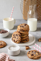 Stack of homemade American brown butter chewy, fluffy and soft chocolate chip cookies on a plate with salt and milk. Biscuits for children. Selective focus.