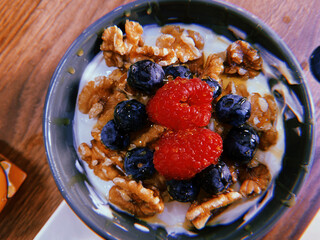 Bowl of nuts, blueberries and raspberries on a white yogurt