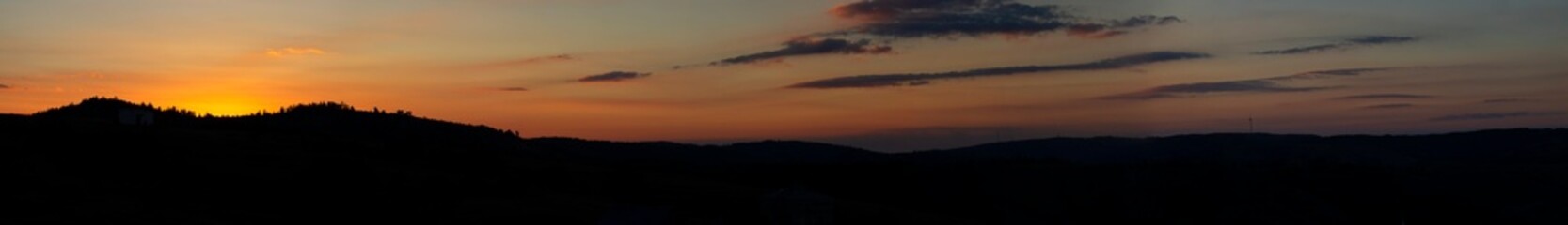 Obraz premium A stunning sunset paints the sky with vibrant orange and red hues, casting a warm glow over the landscape. The peaceful atmosphere invites calm and reflection as day turns into night.