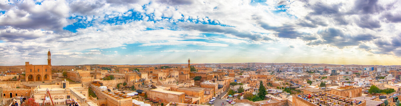 Panoramic view of Midyat, Mardin under a dramatic cloudy sky. The ancient cityscape reveals traditional stone architecture, minarets, and the cultural richness of southeastern Turkey.
