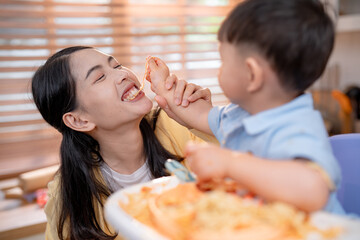 Smiling mother and son share a joyful moment during a meal at home in the afternoon
