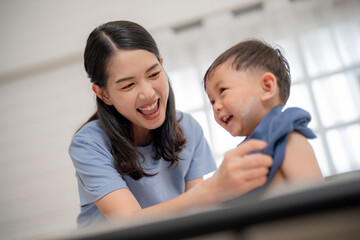 Mother and young child share joyful moments during bath time in a bright, cozy bathroom environment