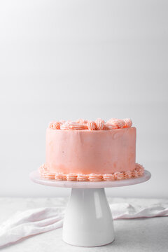 Pink buttercream cake on a cake plate, Cake covered in pink frosting, process of decorating a cake with pink buttercream