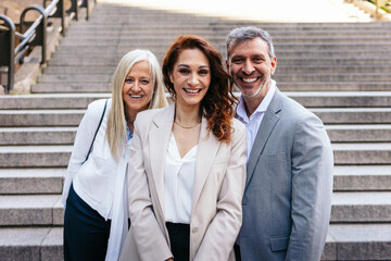 Group of cheerful business people standing together on office building steps