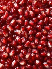 A close up shot showcasing a dense collection of vibrant red pomegranate seeds in a full frame view