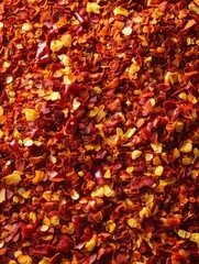A close up view showing a pile of dried crushed red pepper flakes with some yellow pieces mixed in too