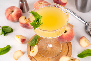 Flat peach martini or margarita lemonade cold fruit drink, summer iced fruit juice cocktail with mint and lemon, on white table