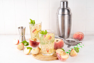 Flat peach lemonade, iced tea or mojito cocktail with fresh fruit garnish. Sweet non-alcohol flat chinese donuts fig peach mocktail with peach slices, mint and crushes ice
