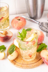 Flat peach lemonade, iced tea or mojito cocktail with fresh fruit garnish. Sweet non-alcohol flat chinese donuts fig peach mocktail with peach slices, mint and crushes ice
