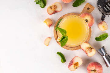 Flat peach martini or margarita lemonade cold fruit drink, summer iced fruit juice cocktail with mint and lemon, on white table