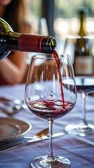 Close-up of red wine pouring into crystal glass with warm light and elegant atmosphere.








