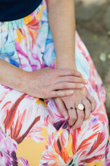 caucasian woman's hands resting on colorful pastel printed skirt, wearing cool chunky rings
