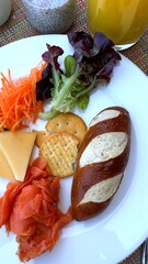 Artisan pretzel, creamy cheese, leafy greens, crackers, carrot ribbons, and tender salmon slices arranged with rustic elegance, ideal for high-end brunch near tourist attraction garden.