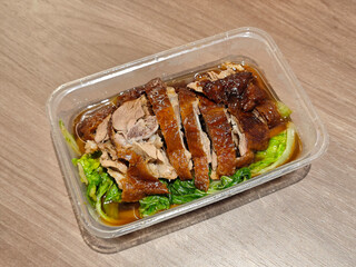 fresh roasted goose with green vegetables in the plastic on the wood table