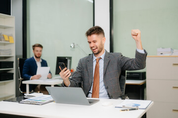 Confident businessman working on finance analysis with a tablet and laptop at office desk