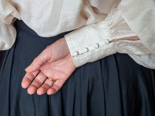 Womens blouse with wide sleeves and many buttons on the cuff. Fashion trends and clothing details. Womans hand with a wedding ring