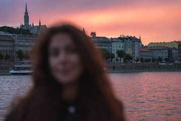 Scenic view of the girl in Budapest at sunset with Matthias Church on a hill, the Danube River,...