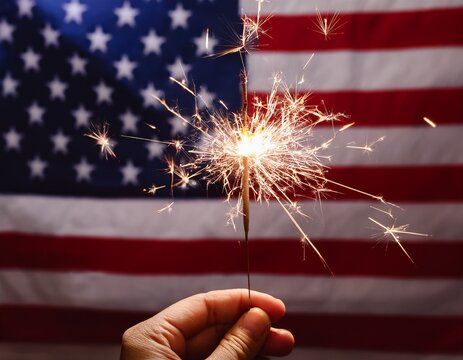 close-up of hand holding burning bengal light in the dark with usa flag in the background
