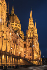 Obraz premium The Hungarian Parliament Building in Budapest, Hungary, glows warmly at night, showcasing its neo Gothic spires, domes, and intricate stonework.