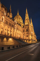 Fototapeta premium The Hungarian Parliament Building in Budapest glows at night, showcasing its neo Gothic architecture, spires, and dome under a clear night sky.