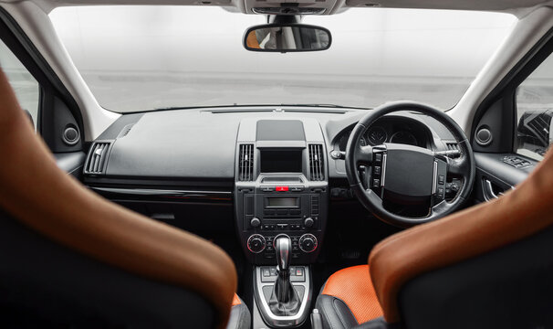 Right-hand drive car interior with tan leather. Car front panel wide angle view: seats, steering wheel, dashboard and center console. 