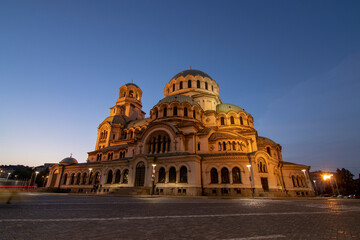 Alexander Nevsky Cathedral in Sofia at dusk, bathed in warm light, showcasing its grand Neo-Byzantine architecture and intricate domes under a fading blue sky.
