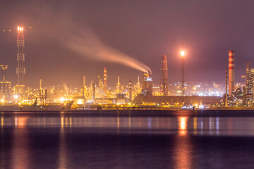 Fototapeta premium Night view of Tüpraş oil refinery in İzmit, Turkey. Industrial lights reflect on water, showcasing the complex refinery infrastructure, highlighting energy production and petroleum processing.
