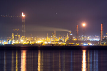 Fototapeta premium Brightly lit İzmit Tüpraş oil refinery at night, reflecting on calm waters. Perfect for energy, industrial, environmental, and commercial projects needing striking, high-resolution imagery.