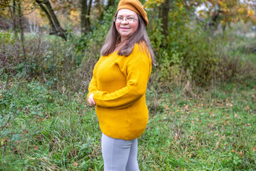 Happy middle-aged woman in mustard sweater and beret, enjoying autumn, smiling, joyful expression, outdoors, fall season, outdoor Mature portrait, forest background