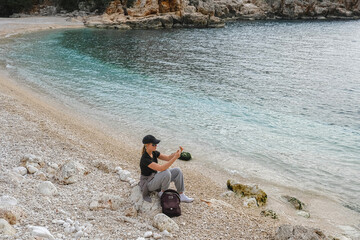 Solo female traveler enjoys scenic coastal view during eco-conscious hiking retreat. Digital nomad...