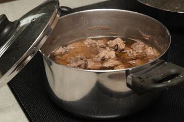 Savory and Delicious Meat Stew Cooking Enthusiastically in a Stainless Steel Pot