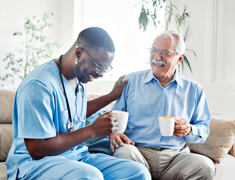 Doctor or nurse caregiver with senior man drinking tea or coffee at home or nursing home - Powered by Adobe