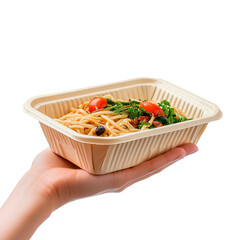 Hand holding a compostable container filled with a pasta dish featuring tomatoes, greens, and other toppings on a dark background.
