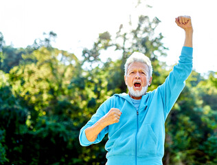 Smiling active senior man jogging exercising and having fun and celebrating success rasing hands...