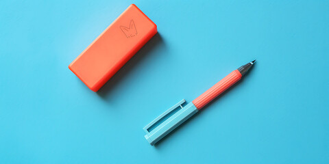 Vibrant orange pencil case with blue and coral pen on bright blue background

