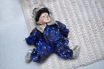 vintage clown in blue shiny suit lying alone on floor, concept of Abandoned, spoiled childhood, nostalgia and innocence, puppet therapy