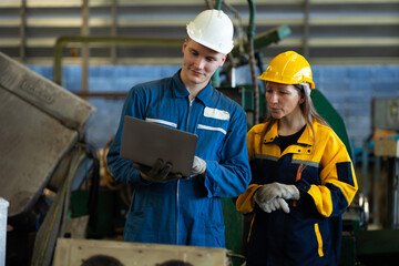 working woman : Caucasian mele and female manufacture technical or factory staff working with holding laptop computer standing at industry factory. Professional Mechanical Engineer