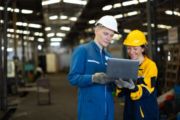 working woman : Caucasian mele and female manufacture technical or factory staff working with holding laptop computer standing at industry factory. Professional Mechanical Engineer