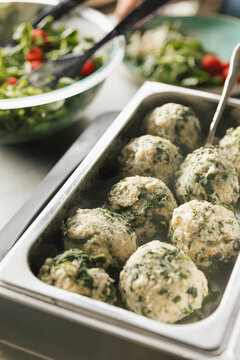Spinat-Semmelkn&ouml;del in Warmhaltebeh&auml;lter, im Hintergrund Salatsch&uuml;ssel

