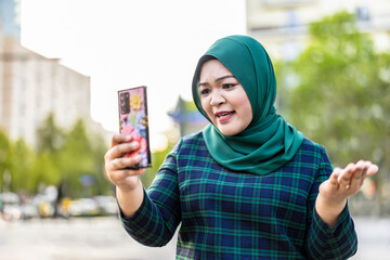 Muslim woman having video call via mobile phone in the city
