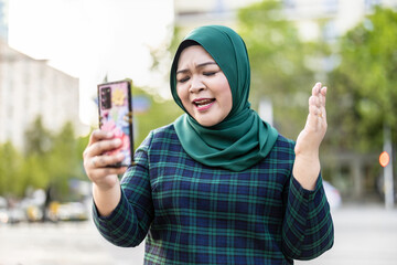Muslim woman having video call via mobile phone in the city
