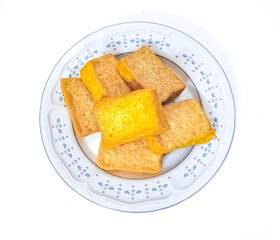 Homemade yellow fried tofus are served on tulip flower white plate. Tofu is one of healthy food contains vegetable protein. In isolated white background.