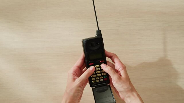 80s 90s retro vintage cell phone being used by a young adult woman, taking old mobile phone with antenna from jeans pocket.